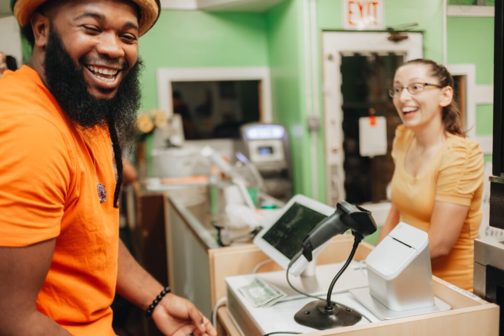 Local store cashier and customer smiling at the checkout counter