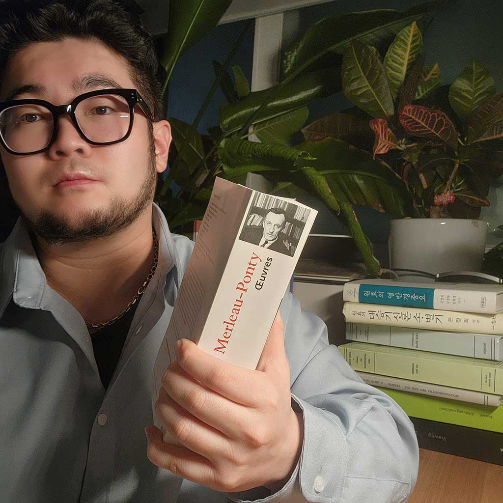 배부른철학자가 메를로 퐁티의 책을 들고 있는 모습